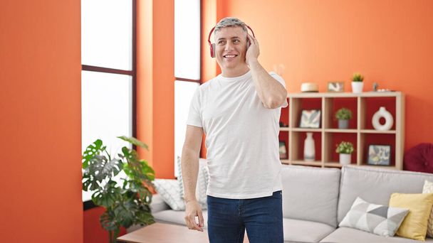 Young caucasian man listening to music smiling at home - Photo, Image