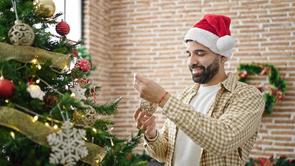 Giovane uomo ispanico decorazione albero di Natale a casa - Foto, immagini