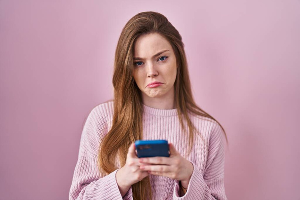 Young caucasian woman using smartphone typing message depressed and worry for distress, crying angry and afraid. sad expression.  - Zdjęcie, obraz