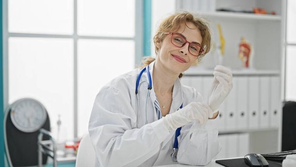 Junge Ärztin mit Handschuhen lächelt in der Klinik - Foto, Bild