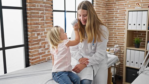 Gondoskodó gyermekorvos és imádnivaló kislány beteg játékosan részt vesz egy orvosi konzultáció a klinika szobában, kényelem és egészségügyi kéz a kézben. - Fotó, kép