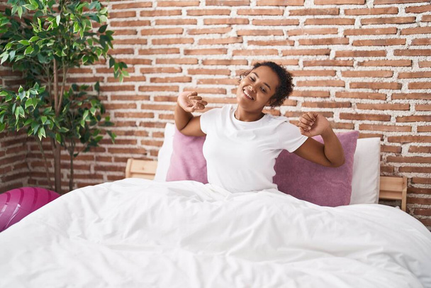 Африканская американка просыпается с протянутыми руками в спальне - Фото, изображение