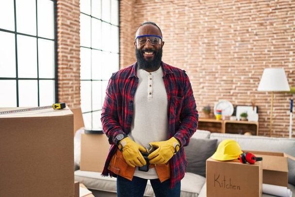 Afro-amerikan adam ev tadilatında çalışıyor. Olumlu ve mutlu görünüyor. Kendine güvenen bir gülümsemeyle dişlerini gösteriyor.  - Fotoğraf, Görsel