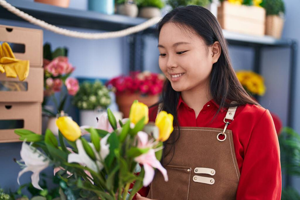 Νεαρή Κινέζα ανθοπώλης κρατώντας μπουκέτο λουλούδια στο ανθοπωλείο - Φωτογραφία, εικόνα