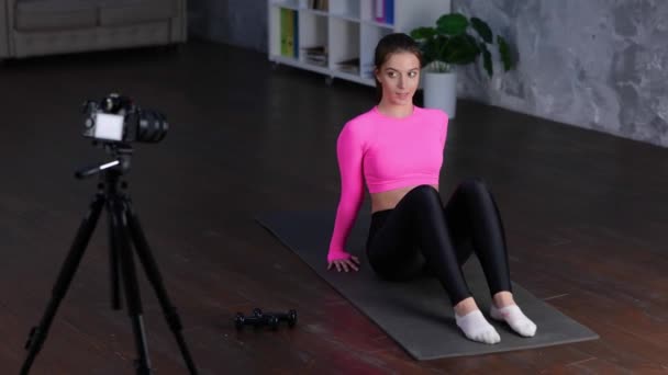 Jeune femme souriante faisant des exercices abdominaux sur le tapis tout en filmant une vidéo avec une caméra sur un trépied. Style de vie sain actif, concept d'entraînement. Vidéo en temps réel. - Séquence, vidéo