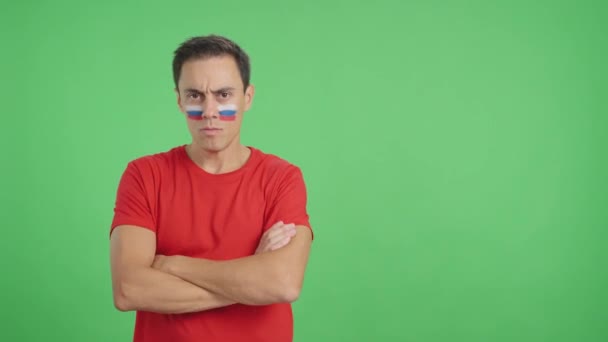 Βίντεο στο στούντιο με chroma ενός αξιοπρεπούς και σοβαρού άνδρα με ρωσική σημαία ζωγραφισμένη στο πρόσωπο κοιτάζοντας την κάμερα με αξιοπρέπεια - Πλάνα, βίντεο