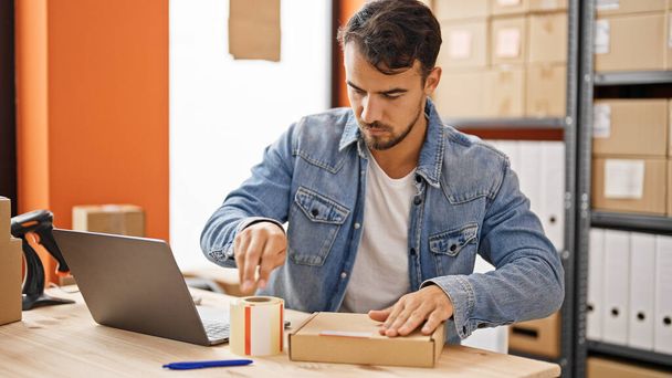 Joven hispano hombre comercio electrónico trabajador de negocios embalaje caja de cartón en la oficina - Foto, Imagen