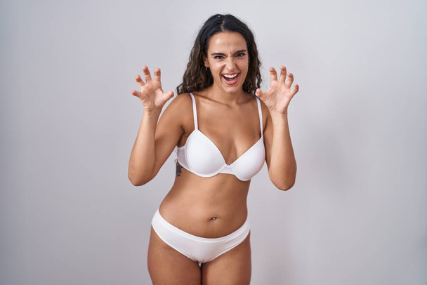 Fiatal spanyol nő visel fehér fehérnemű mosolygós vicces csinál karom gesztus mint macska, agresszív és szexi kifejezés  - Fotó, kép