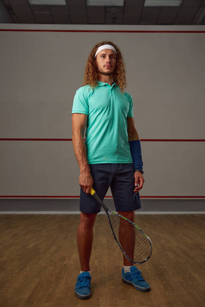 Portrait of confident male squash player standing with racket ready for game looking confidently at camera - Photo, Image