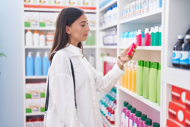 Молода красива іспаномовна жінка клієнт тримає зубну пасту в аптеці
 - Фото, зображення