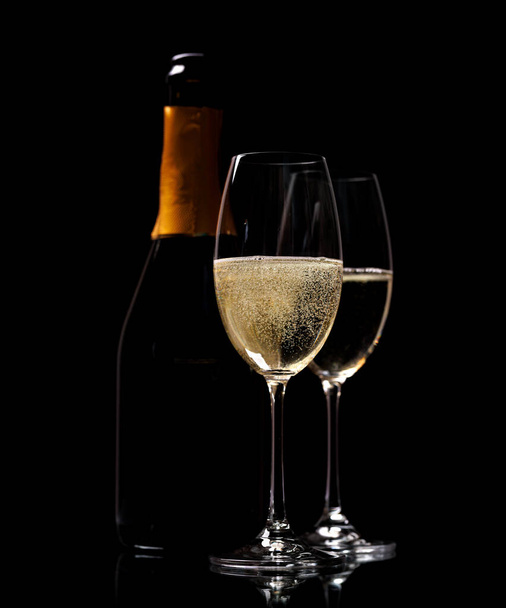 Két pezsgős pohár és üveg fekete háttérrel, fénymásoló felülettel - Fotó, kép