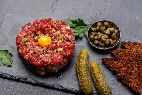 Savory beef tartare with pickled gherkins and brown bread toasts - Photo, Image