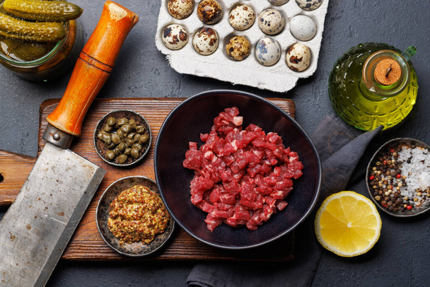 Cooking savory beef tartare with pickled gherkins and brown bread toasts. Flat lay - Photo, Image