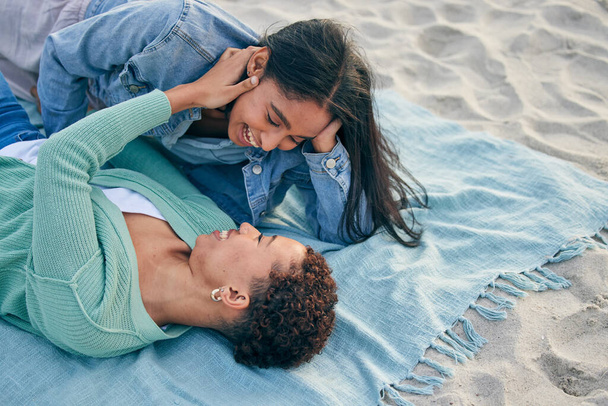 Liebe, Picknick und Lächeln, lesbisches Paar auf Decke zusammen, Händchen haltend auf Sand und Urlaubsabenteuer. Lgbt Frauen, Bindung und Entspannung im Urlaub am Meer mit Romantik, Stolz und glücklichem Liegen in der Natur - Foto, Bild