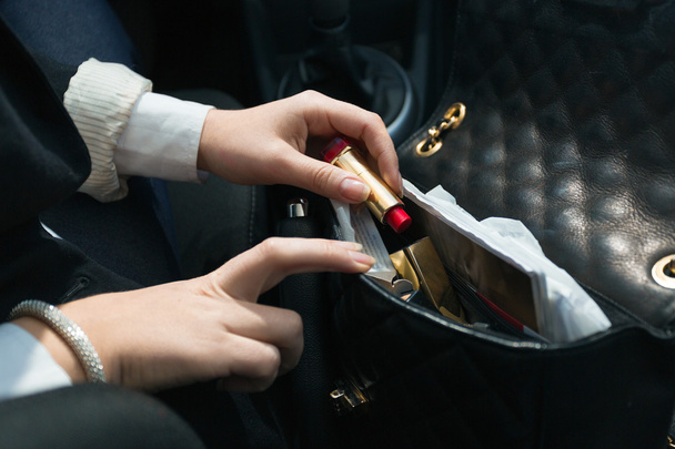 femme assise dans la voiture et sortant le rouge à lèvres du sac à main
 - Photo, image