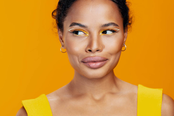 Femme cosmétologie coloré style cosmétique beauté belle créative peau studio africain portrait visage jaune sourire fashion model noir maquillage - Photo, image