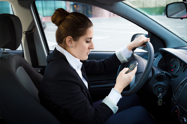 jonge zakenvrouw rijden een auto en het gebruik van de telefoon - Foto, afbeelding