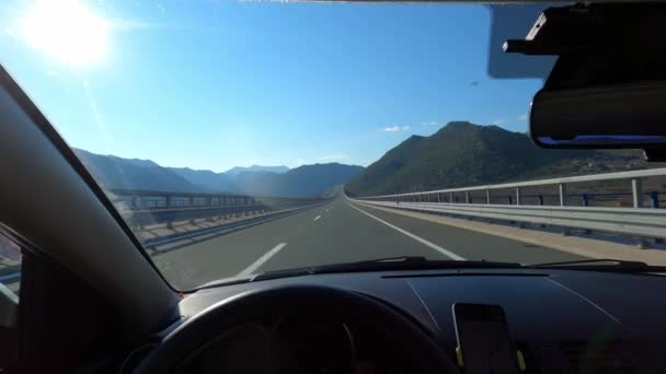 Uitzicht van achter het stuur van een auto op een snelweg in de bergen tegen een blauwe horizon. Hoge kwaliteit 4k beeldmateriaal - Video