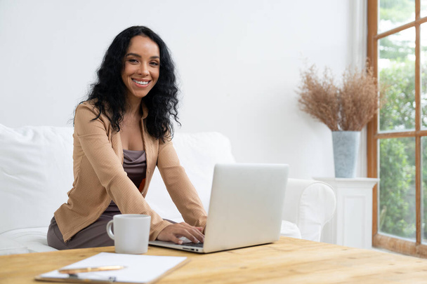 Αφροαμερικανή γυναίκα που χρησιμοποιεί φορητό υπολογιστή για κρίσιμες εργασίες στο διαδίκτυο. Γραμματέας ή online περιεχόμενο γραπτώς εργασίας στο σπίτι. - Φωτογραφία, εικόνα