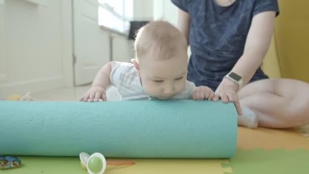 Ένα μωράκι που παίζει με το στρώμα γιόγκα. Μεσαίο πλάνο - Πλάνα, βίντεο