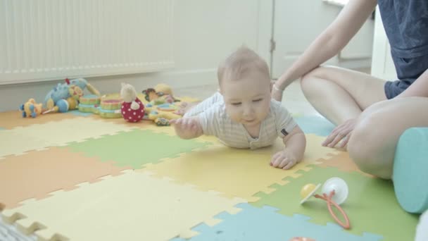 Een kleine baby kruipt op het tapijt naar zijn speelgoed. Tussenschot - Video