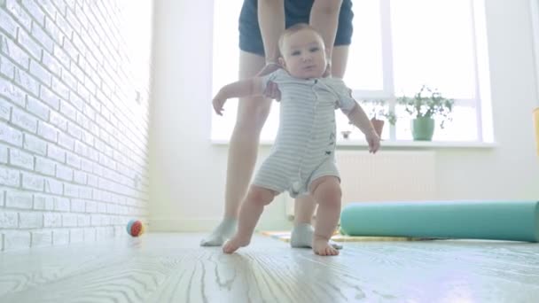 Mother teaching her baby how to walk. Mid shot - Footage, Video