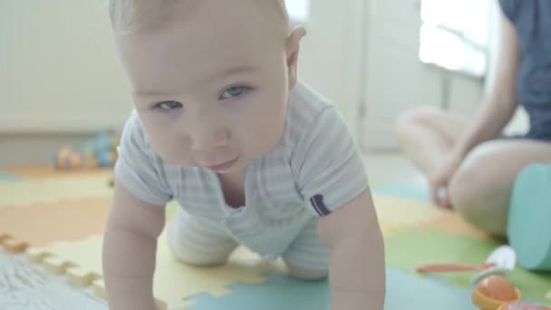 Ein kleines Baby krabbelt auf dem Boden und blickt in die Kamera. Mittelschuss - Filmmaterial, Video