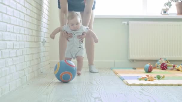 Madre enseñando a su bebé a caminar y jugar con una pelota. Mid shot - Metraje, vídeo