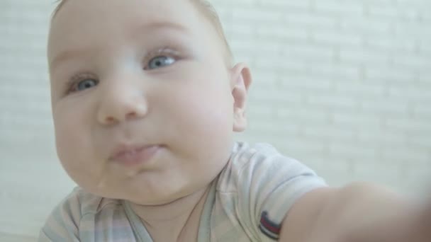 Een kleine baby reikt naar de camera en kwijlt. Tussenschot - Video