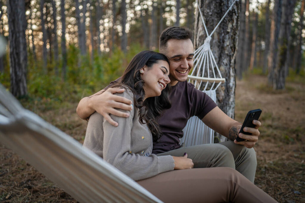 Man and woman young adult couple in nature take self portrait photo selfie ugc use mobile phone smartphone or make a video call - Photo, Image