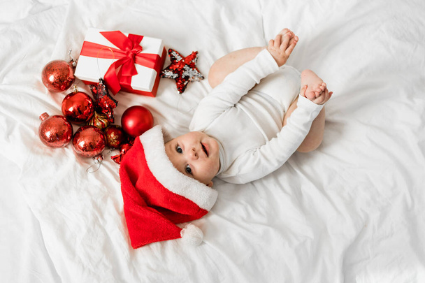 Hermoso bebé celebra la Navidad. Vacaciones de Año Nuevo. Bebé en un traje de Navidad con regalo
. - Foto, Imagen