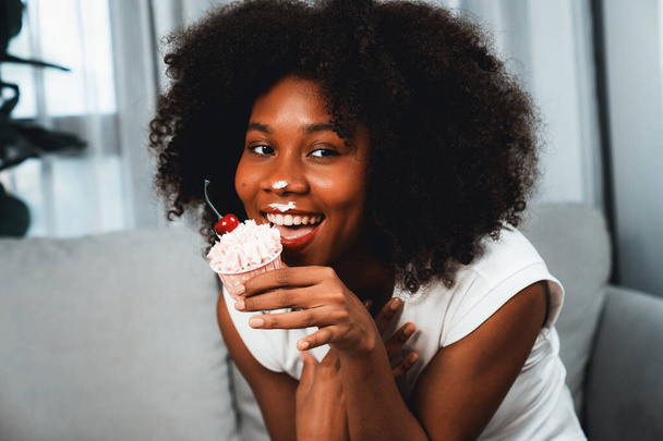 Funny beautiful young African blogger on mess face presenting cupcake in concept special cuisine. Content creating of social media online with favorite tasty sweets bakery dish. Tastemaker. - Photo, Image