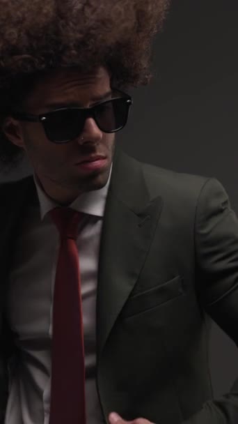 verticale video van elegante jonge zakenman met een zonnebril op zoek naar kant en knoop pak in de voorkant van de politie lichten achtergrond - Video