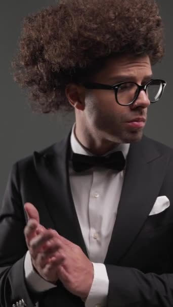 selbstbewusster Geschäftsmann mit zur Seite blickender Brille und Handflächen, Händchen haltend in Taschen auf grauem Hintergrund - Filmmaterial, Video