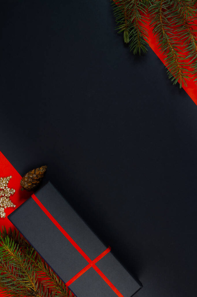 Ein Weihnachtsbaum, Dekorationen, Lichter und eine Geschenkbox auf schwarzem Hintergrund. Ansicht von oben. - Foto, Bild