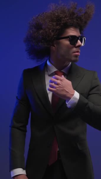 selbstbewusster Modemann mit seitlichem Blick und roter Krawatte, der die Hände in den Taschen hält und vor Polizeilichtern posiert - Filmmaterial, Video