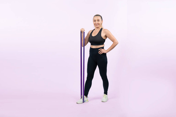 Full body length shot athletic and sporty senior woman with fitness resistance band on isolated background. Healthy active physique and body care lifestyle after retirement. Clout - Photo, Image