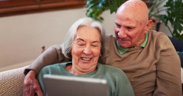 Idős pár, tabletta és nevetni otthon olvasás közben a szociális média post, hírek app és ebook kanapén. Happy old man, woman and relax to scroll digital blog, online vásárlás és vicces mém a társalgóban. - Felvétel, videó