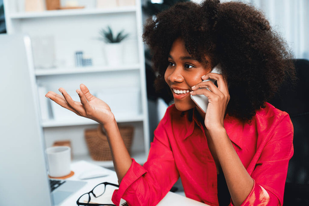 Afrikai nő beszél munkatársával vagy barátjával telefonon, és boldog arccal nézi a képernyőt. Eredmény a jó hírrel rendelkező cégnél betöltött pozíció népszerűsítéséért. Kóstoló. - Fotó, kép
