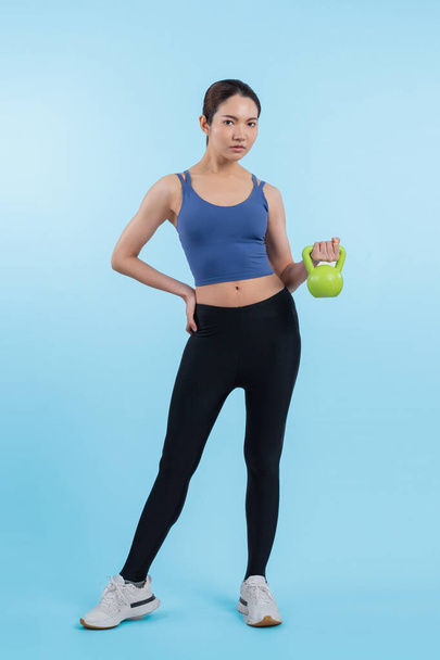 Élénk energikus nő csinál kettlebell súlyemelés gyakorlat elszigetelt háttérrel. Fiatal sportos ázsiai nő erő és kitartás képzés ülésén, mint a test edzés rutin. - Fotó, kép