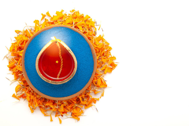 Diwali diya (hliněná olejová lampa) je vidět z horního pohledu, umístěn na oranžové marigold okvětní lístky, izolované na bílém pozadí. - Fotografie, Obrázek