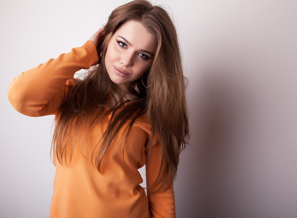 Young sensual & beauty model girl iin casual orange sweater pose in studio. - Foto, afbeelding
