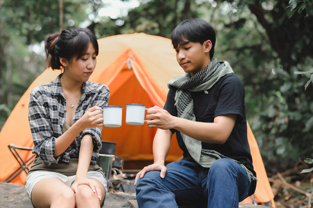 Junge Leute halten Wasserbecher zum Trinken im Wald. Campingplatz trinkt Kaffee und sauberes Wasser auf Trekkingausflügen. - Foto, Bild