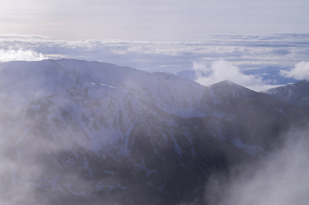 Heiter majestätischer Bergblick mit ätherischem Wolkenspiel, der Kasprowy Wierchs winterliche Anziehungskraft perfekt für Natur- und Reisethemen einfängt. - Foto, Bild
