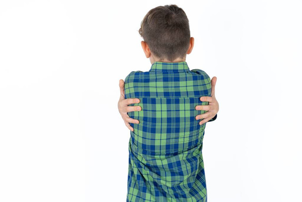 handsome teen boy wearing plaid shirt over white background hugging herself happy and positive from backwards. Self love and self care - Photo, Image