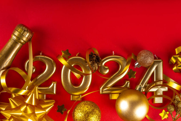 Ευτυχισμένο το νέο έτος 2024 φόντο ευχετήρια κάρτα με αριθμούς χρυσού, μπουκάλι σαμπάνιας, serpentine, Χριστούγεννα και Πρωτοχρονιά διακοσμήσεις σε κόκκινο φόντο αντίγραφο χώρο - Φωτογραφία, εικόνα