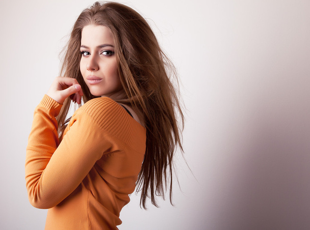 Young sensual & beauty model girl iin casual orange sweater pose in studio. - Foto, imagen