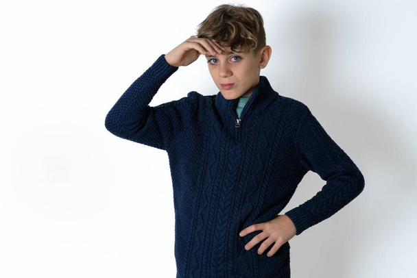 Handsome Caucasian teen boy in blue sweater having problems, worried and stressed holds hand on forehead. - Photo, Image