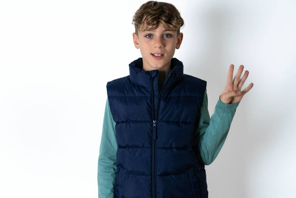schöner kaukasischer Teenager-Junge auf weißem Studiohintergrund, der mit Finger Nummer vier zeigt und nach oben zeigt, während er selbstbewusst und glücklich lächelt. - Foto, Bild