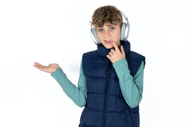 Positive handsome caucasian teenager boy on white studio background advert promo touch finger teeth - Foto, Imagen